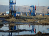 Baku - Azerbaijan: oil contamindated soil and pumpjacks near the harbour, below Bibi Heybat Mosque - pollution - photo by F.MacLachlan