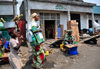 Goma, Nord-Kivu, Democratic Republic of the Congo: street scene - commerce - woman in traditional clothes and girl with sugar cane - Kerrygold logo - piles of Rwenzori and Riham power boxes - photo by M.Torres