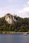 Slovenia - Gondolier rowing tourists across Lake Bled with castle on cliff in background - photo by I.Middleton